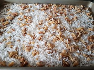 Spread Coconut And Nuts In A Baking Sheet