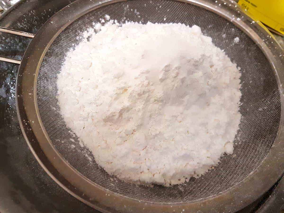 In a sieve add flour and cornstarch